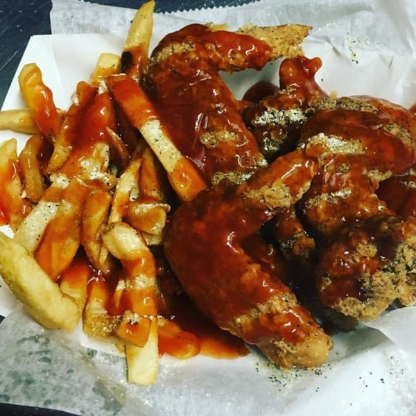 Harold's Chicken Shack's fried chicken wings and french fries, generously covered in mild sauce.